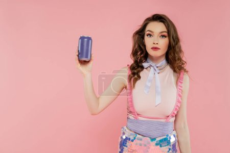 Puppenkonzept, attraktive junge Frau mit welligem Haar, Limonadendose mit kohlensäurehaltigem Getränk, Werbung, stehend auf rosa Hintergrund, Modemodel in stylischem Outfit, Weiblichkeit, Puppenpose 