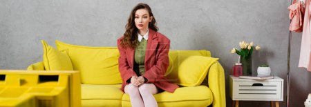 Photo for Concept photography, beautiful well dressed woman with wavy hair sitting on yellow couch, stylish house interior, vase with tulips, watching tv, posing like a doll, housewife lifestyle, banner - Royalty Free Image
