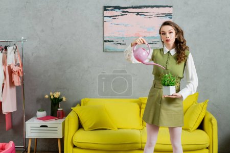 eco-friendly, housekeeping concept, young woman with wavy hair watering green potted plant, botany, housekeeping, beautiful housewife looking at camera and standing in living room 