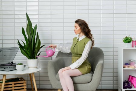 concept photography, eco-friendly, housekeeping concept, beautiful woman with wavy hair watering plant, green thumb, botany, sitting on armchair, housekeeping, housewife with pink watering can 