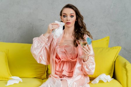 emotional stress, sad woman with smudged mascara sitting on yellow couch, housewife with crying eyes holding napkin and cocktail, feeling lonely and depressed, heartbroken wife at home 