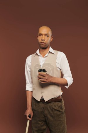 Inklusion, mutiger afrikanisch-amerikanischer Mann mit Myasthenia-Gravis-Syndrom, stehend mit Pappbecher und Gehstock, dunkelhäutiger Mann mit chronischer Krankheit auf braunem Hintergrund, Coffee to go 