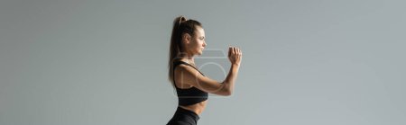 Photo for Side view of brunette fit sportswoman working out on grey, banner, active lifestyle concept - Royalty Free Image