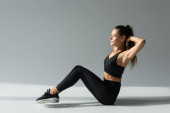 Fit woman in black sports bra, leggings and sneakers exercising while sitting in sunlight on grey  mug #664862664
