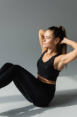 Confident brunette sportswoman in black sports bra and leggings working out on grey background  hoodie #664862668