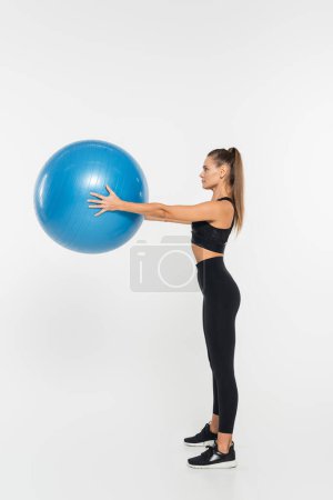 Foto de Deportista en forma sosteniendo la pelota de fitness mientras hace ejercicio sobre fondo blanco, concepto de mujer atlética - Imagen libre de derechos
