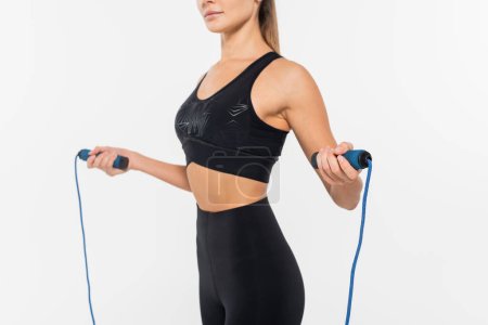 Cropped view of fit sportswoman holding jump rope isolated on white, healthy and fit concept