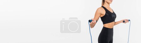 cropped view of fit sportswoman holding jump rope isolated on white, banner, healthy and fit concept