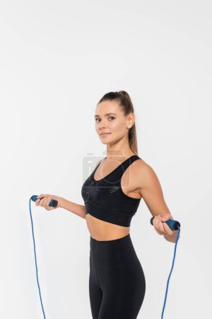 woman in fitness clothes holding skipping rope, training isolated on white, healthy and fit concept