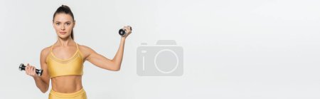 Sportlerin in Fitnessbekleidung blickt in die Kamera, Training mit Hanteln isoliert auf weiß, Banner