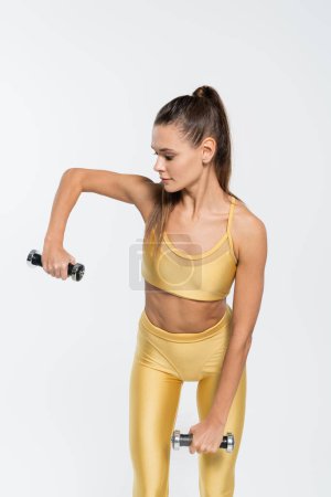 Fit Frau im aktiven Tragetraining mit auf Weiß isolierten Kurzhanteln, Fitness-Motivationskonzept 