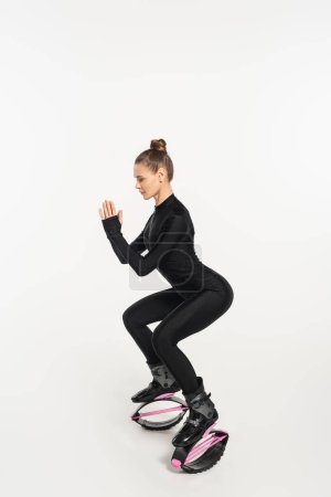 woman in jumping boots exercising on white background, kangoo jumping shoes, full length, trend