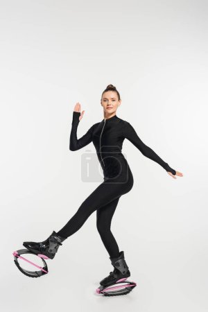 energía, mujer en zapatos de kangoo saltando ejercitando sobre fondo blanco, deportista en botas de salto 