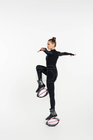 physical activity, white background, woman in black jumpsuit and kangoo jumping shoes