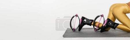 Photo for Cropped view of woman in active wear exercising on fitness mat in kangoo jumping shoes, banner - Royalty Free Image