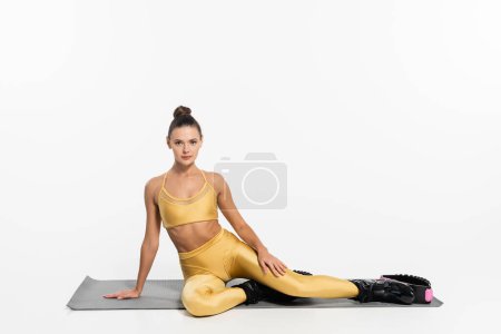 Kangoo-Springschuhe, junge Frau in aktiver Kleidung sitzt auf Fitnessmatte, Fitness und Sport 