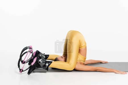 flexible woman in active wear stretching body on fitness mat, kangoo jumping shoes, motivation  tote bag #664865642