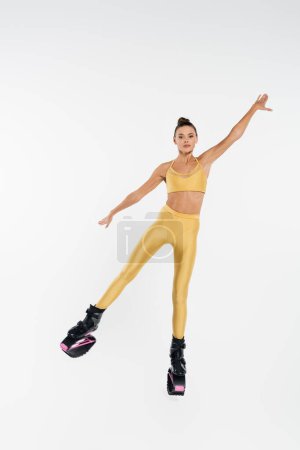 energetic woman in kangoo jumping shoes toned body, motivation and balance, white background 