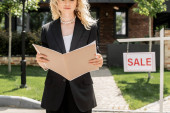 cropped view of property agent with folder near building and signboard with for sale lettering t-shirt #664924424