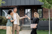 real estate broker with folder giving key to overjoyed interracial couple near new city cottage Longsleeve T-shirt #664924556