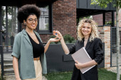 blonde real estate agent giving key from new house to pleased african american buyer tote bag #664924574