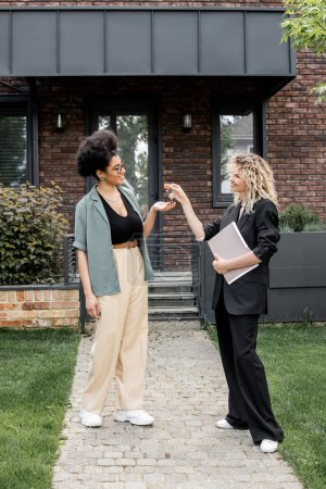 Téléchargez les photos : Heureuse femme afro-américaine prendre la clé de nouveau chalet de l'agent immobilier - en image libre de droit