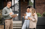 cheerful multiethnic lesbian couple with coffee to go talking with real estate agent near new house Poster #664925342