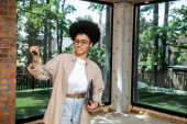 positive african american real estate agent holding folder and keys in modern city cottage Stickers #664926044