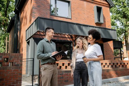 positive real estate agent talking to interracial lesbian couple with coffee to go near city cottage Stickers 664926174