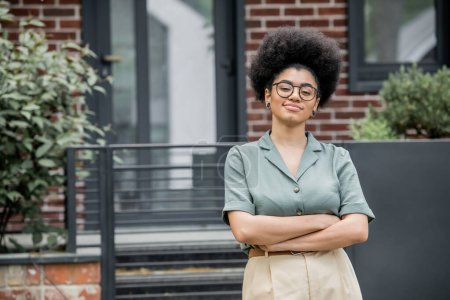 confident african american real estate agent in eyeglasses looking at camera outdoors