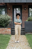 full length of smiling african american real estate agent standing with folded arms near cottage magic mug #664926518