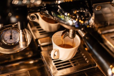 Téléchargez les photos : Vue grand angle de café versant dans la tasse blanche de la machine à café au soleil dans le café - en image libre de droit