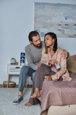 pregnancy and abortion concept, man calming african american woman, water, birth control pills