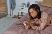 african american woman lying on bed, looking at pregnancy test, making decision, abortion concept hoodie #668923878