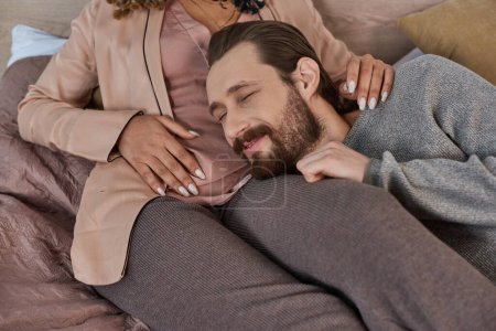 future parents, happiness, bearded man listening belly of pregnant african american wife in bedroom