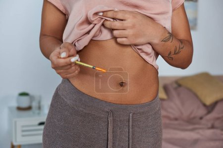 Téléchargez les photos : Femme afro-américaine faisant des injections hormonales dans le ventre, tatouage, concept de grossesse, cultivé - en image libre de droit