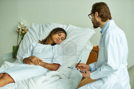 bearded doctor with clipboard standing near sad african american woman, private ward, consult