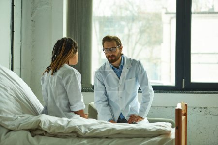 doctor masculino hablando con mujer afroamericana, explicando diagnóstico, sala privada, hospital