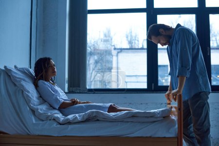 man grieving near depressed african american wife, standing near hospital ward, miscarriage concept