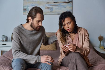 bearded man calming down african american girlfriend with pregnancy test, unexpected news, shock mug #668927606
