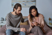 bearded man calming down african american girlfriend with pregnancy test, unexpected news, shock Mouse Pad 668927606