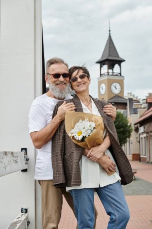 happy elderly couple in sunglasses, man hugging woman with flowers, summer, outlet, bouquet, romance