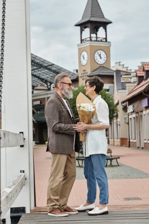 Téléchargez les photos : Heureux couple âgé dans des lunettes de soleil, homme regardant femme avec des fleurs, été, bouquet, romance - en image libre de droit