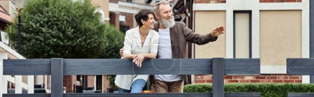 joyeux couple âgé, homme pointant du doigt, ensemble, toile de fond urbaine, population vieillissante, bannière