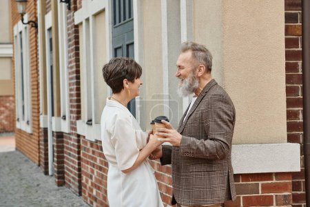 happy senior couple, coffee to go, building, elderly man and woman, laughter, looking at each other