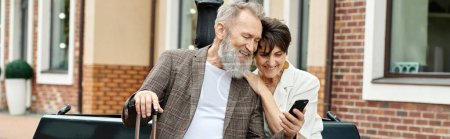 pancarta, pareja de ancianos, feliz hombre mayor sosteniendo teléfono inteligente, sentado con la mujer usando gadget