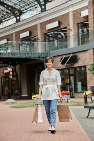 zufriedene Seniorin, die mit Einkaufstüten auf städtischen Straßen, im Einzelhandel, in der Stadt, im Freien spaziert