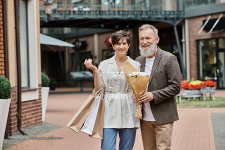 Photo for Happy elderly couple, shopping, bouquet of flowers, romance, active seniors, aging population, city - Royalty Free Image