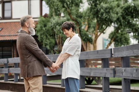 woman and bearded man holding hands, looking at each other, date, romance, happy elderly couple