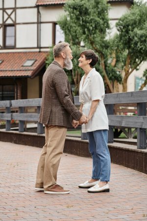 woman and bearded man holding hands, date, senior romance, happy elderly couple, full length